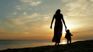 stock-footage-mother-with-baby-walking-on-sea-coast-silhouettes-sunset